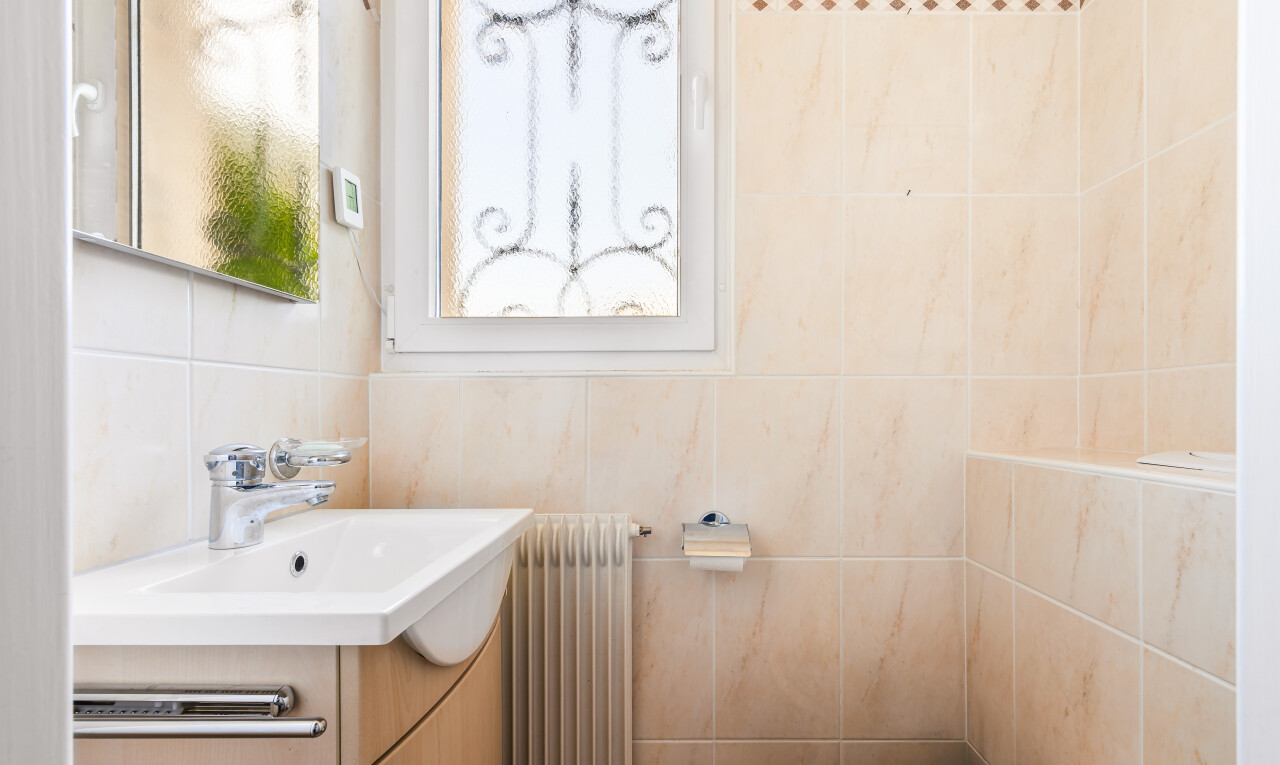 salle de bains avec lavabo (ou coiffeuse selon le contexte), miroir, inside property, radiateur, et toilette