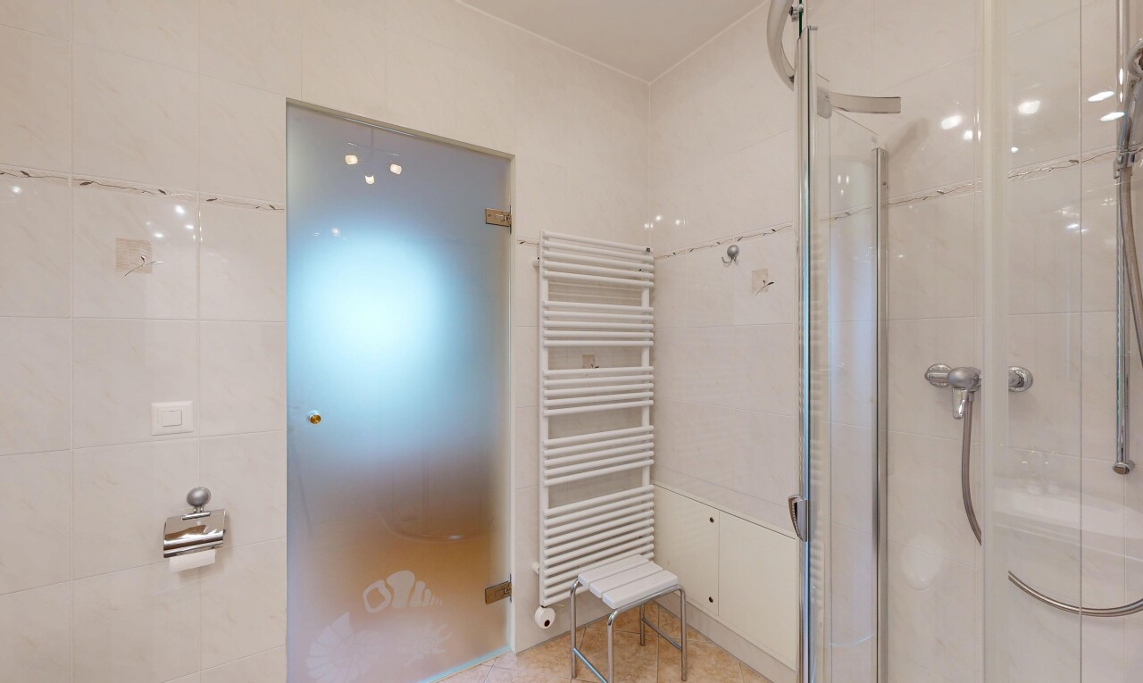 salle de bains avec radiateur, douche, chauffe-serviettes, salle de bain complète, et inside property