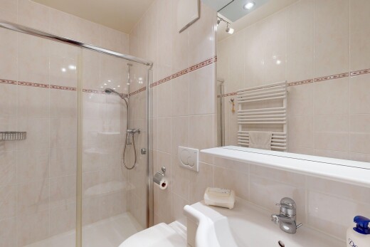 full bathroom with radiator heating unit, a stall shower, a towel warming rack, tile walls, and vanity