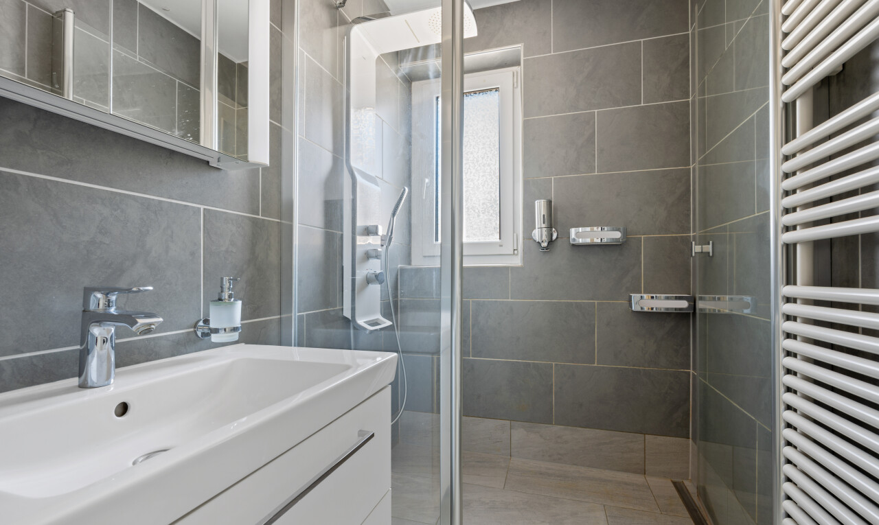 salle de bains avec chauffe-serviettes, lavabo (ou coiffeuse selon le contexte), miroir, light floor, et inside property