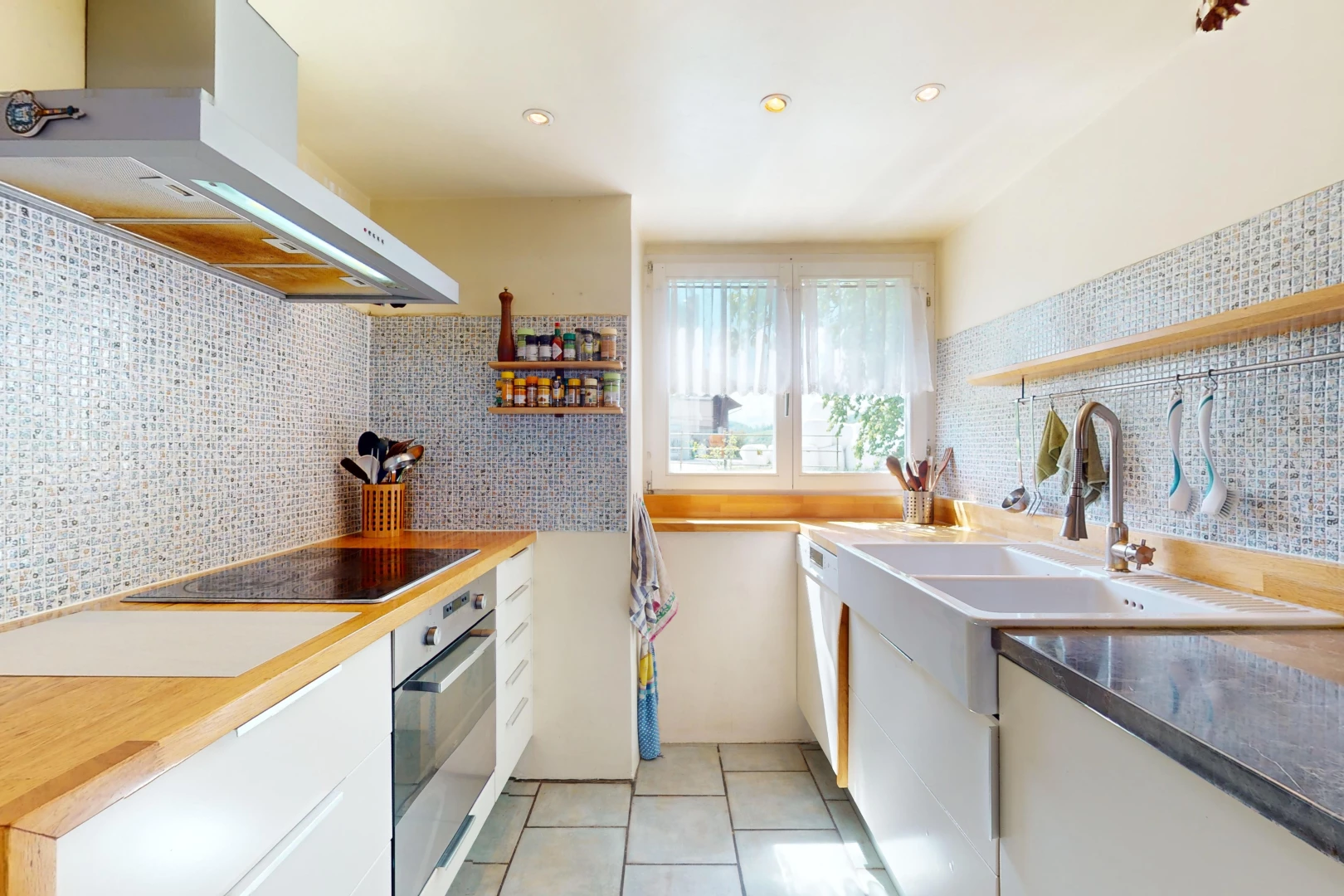 küche mit ofen, weiße schränke, backsplash, dunstabzugshaube, und natürliches licht