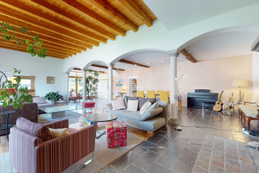wohnzimmer mit balkendecke, dekorative säulen, fliesenboden, und natürliches licht