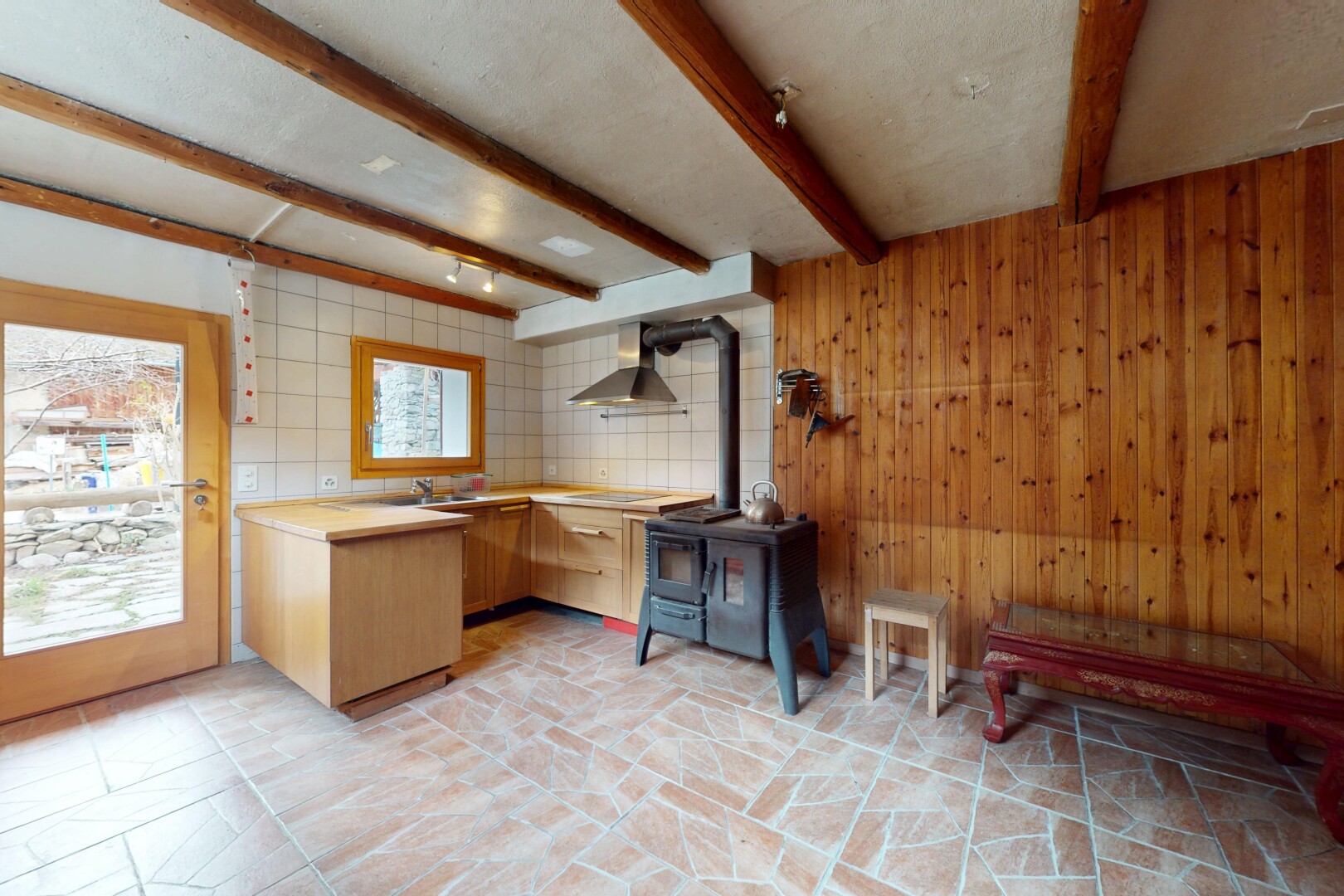 küche mit holzwand, holzofen, dunstabzugshaube, balkendecke, und natürliches licht
