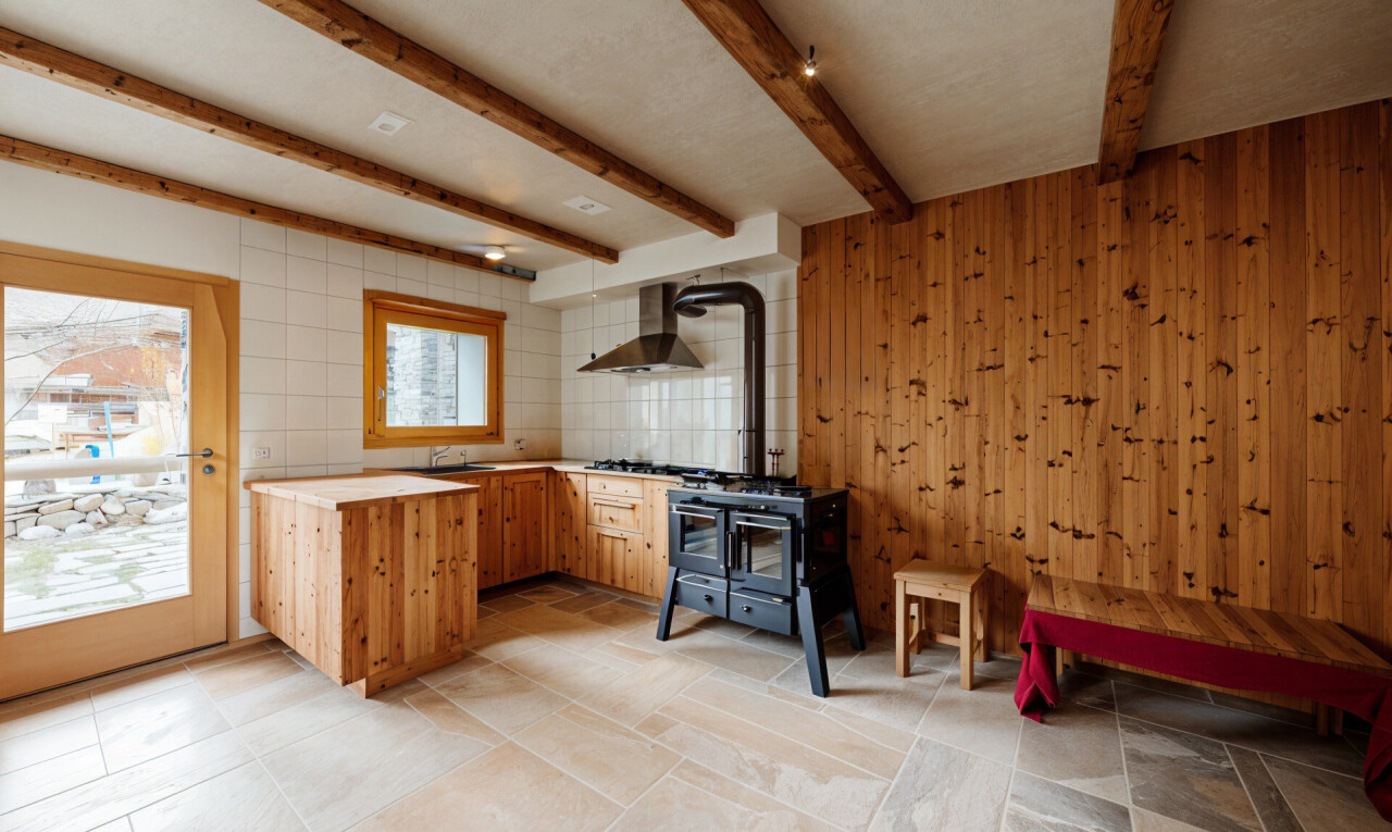 innenraum mit dunstabzugshaube, balkendecke, herd, holzofen, und arbeitsplatten