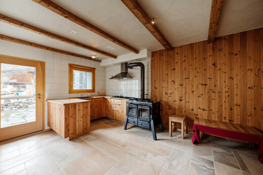 espace intérieur avec cuisinière, poêle à bois, plans de travail, hotte, et plafond à poutres