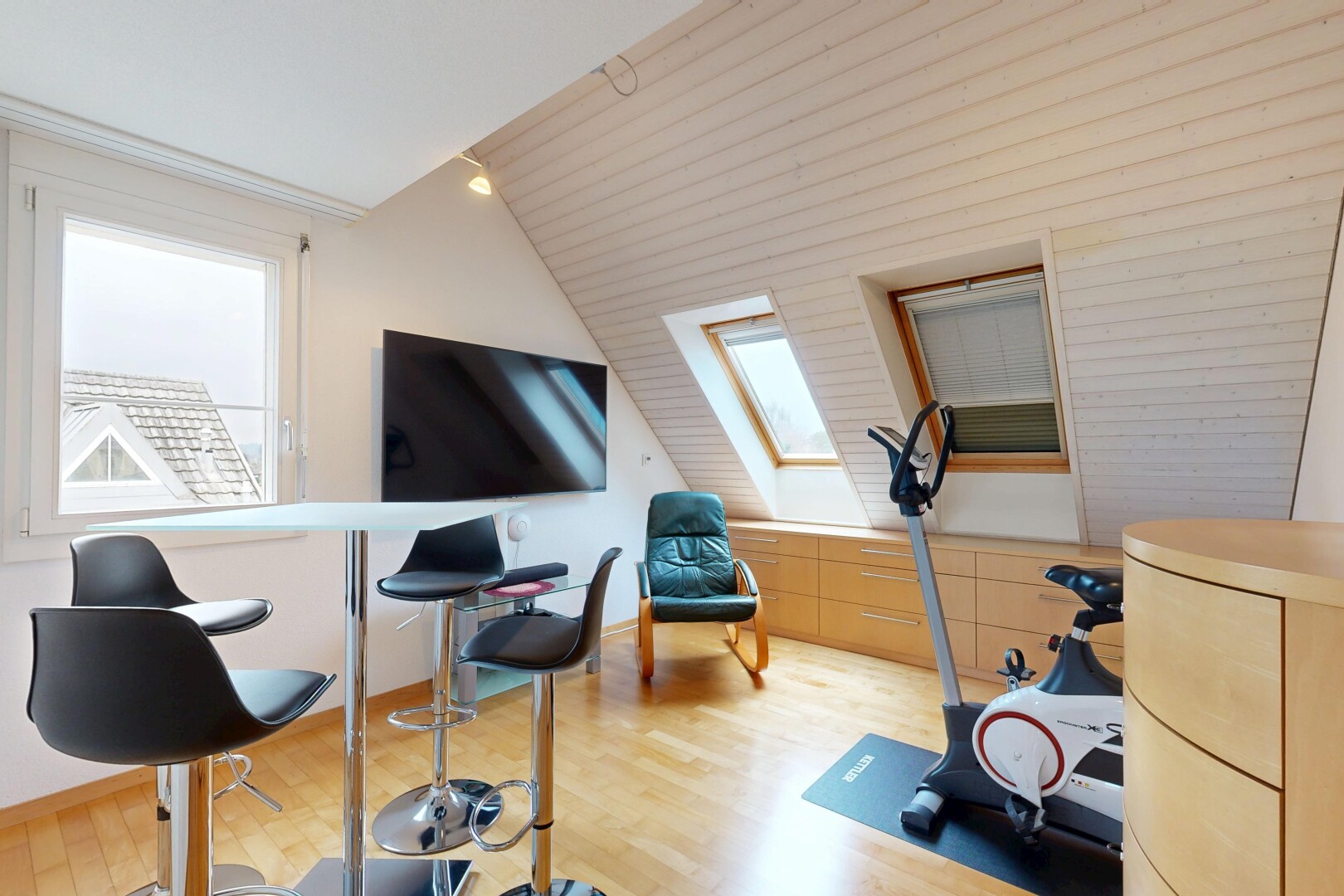 fitnessstudio mit fernseher, holzfußboden, wood finish floor, dachschräge, und vaulted ceiling