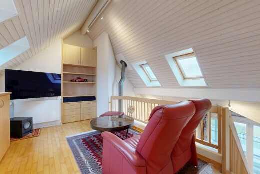 living area featuring a skylight, lofted ceiling, a wood stove, built in shelves, and light wood-style floors