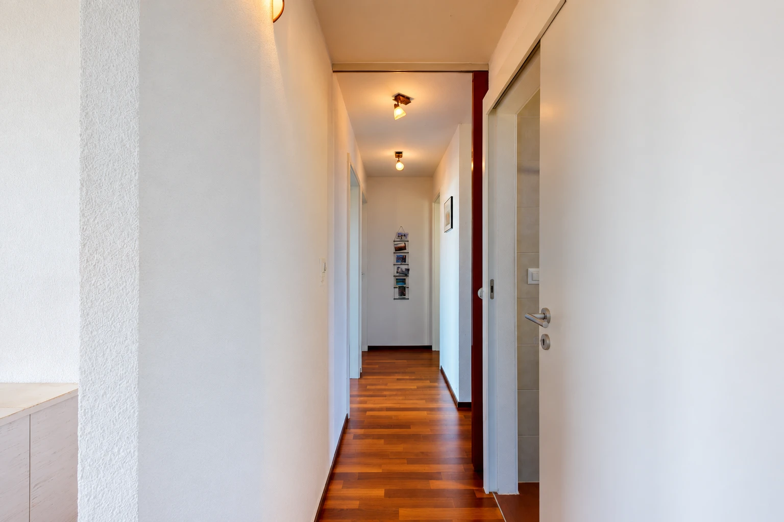 couloir avec sol en finition bois, wood finish floor, inside property, cloison sèche, et drywall