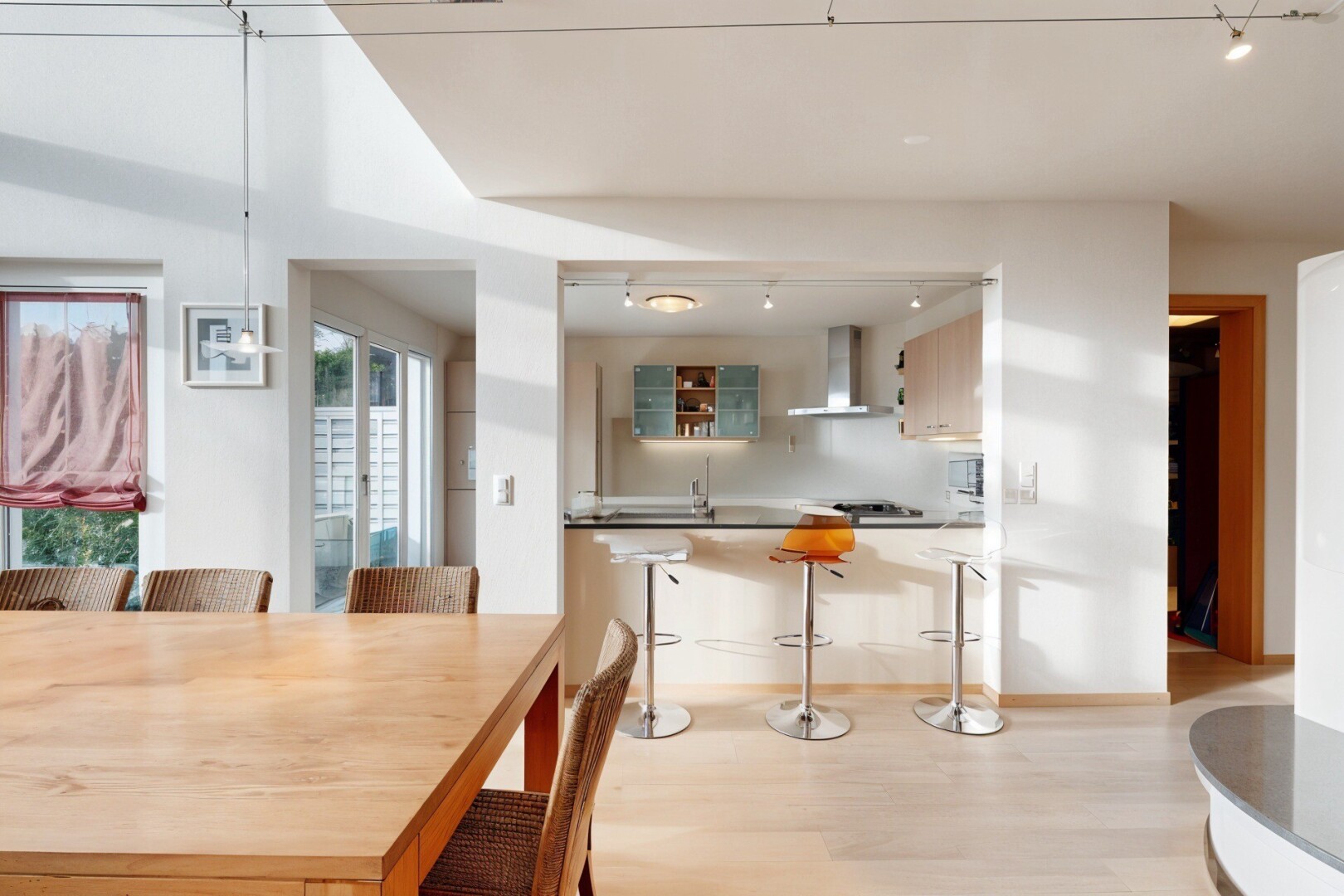 kitchen with track lighting, a kitchen bar, light wood finished floors, and wall chimney exhaust hood