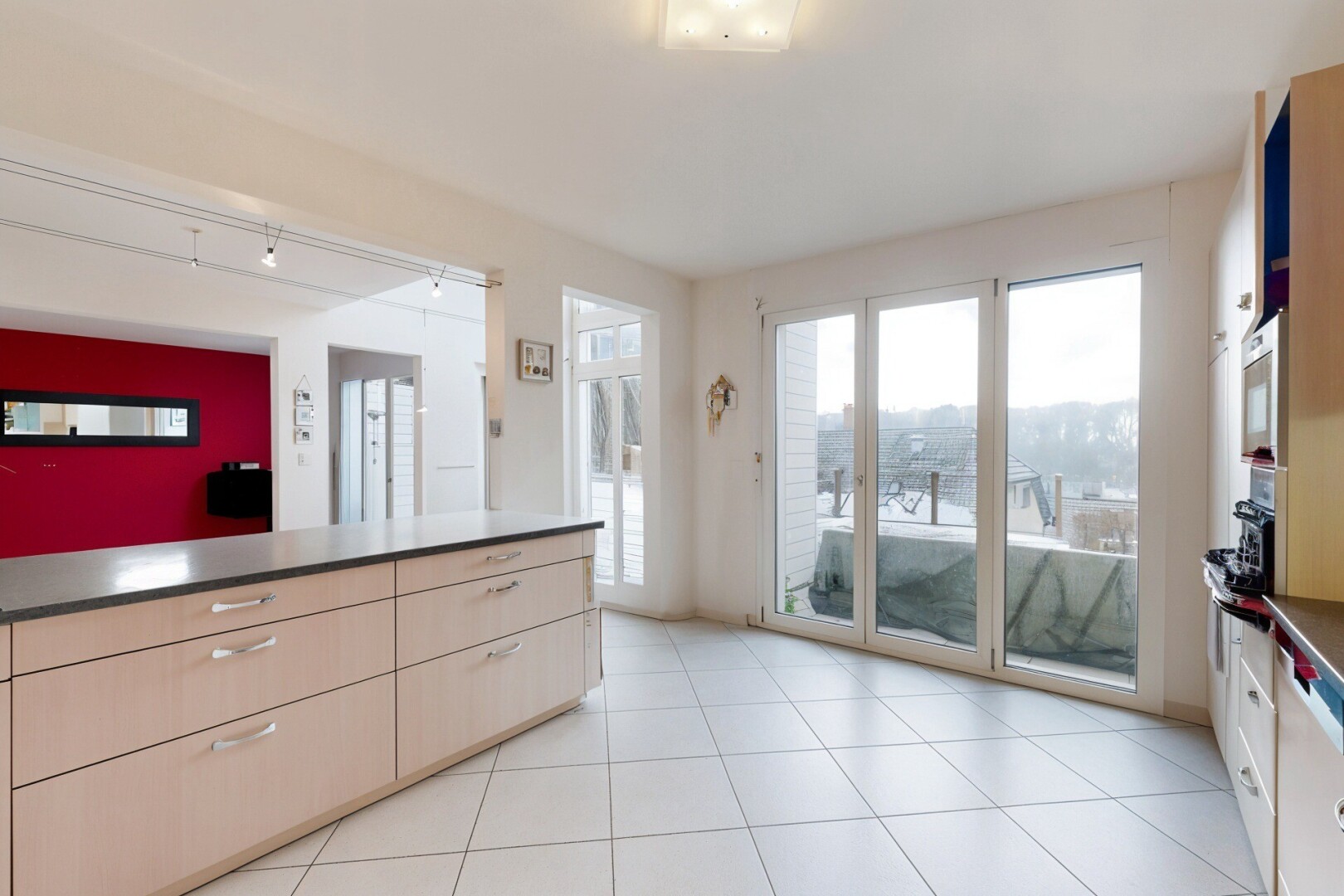 kitchen featuring light tile patterned floors, rail lighting, dark countertops, and stainless steel microwave