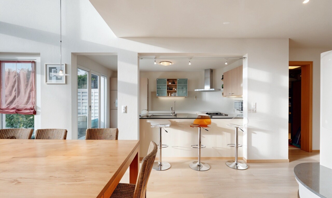 kitchen with track lighting, a kitchen bar, light wood finished floors, and wall chimney exhaust hood