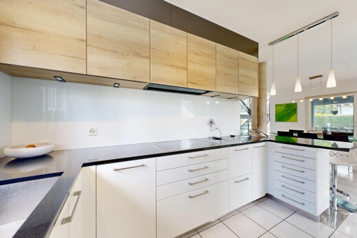 kitchen featuring a peninsula, light tile patterned floors, a kitchen breakfast bar, hanging light fixtures, and light wood finish cabinetry