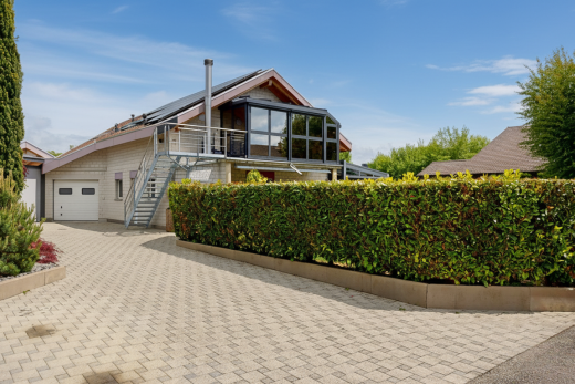 view of property with solar panels, decorative driveway, a balcony, and an attached garage