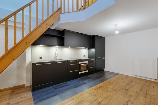 cuisine avec armoires à panneau plat, sol en finition bois, wood finish floor, radiateur, et armoires noires