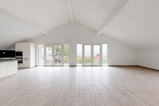 pièce vide avec cloison sèche, drywall, plafond à poutres, beamed ceiling, et sol en finition bois