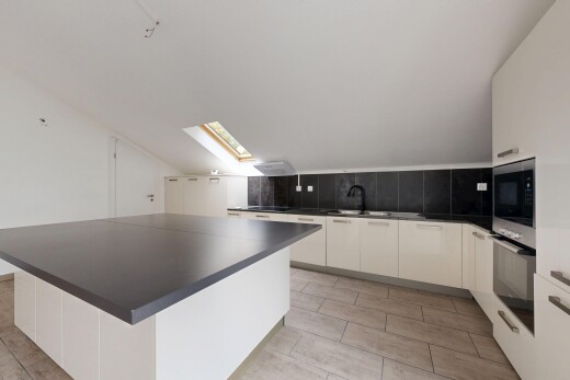 cuisine avec armoires à panneau plat, plans de travail, îlot de cuisine, armoires blanches, et puits de lumière