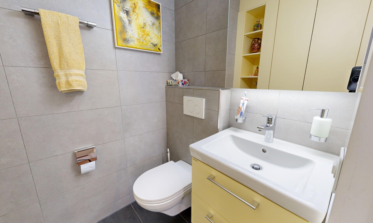 salle de bains avec mur en carrelage, tile wall, miroir, lavabo (ou coiffeuse selon le contexte), et toilette