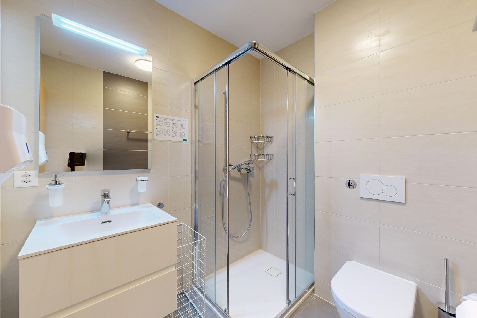 salle de bains avec toilette, douche, mur en carrelage, et évier
