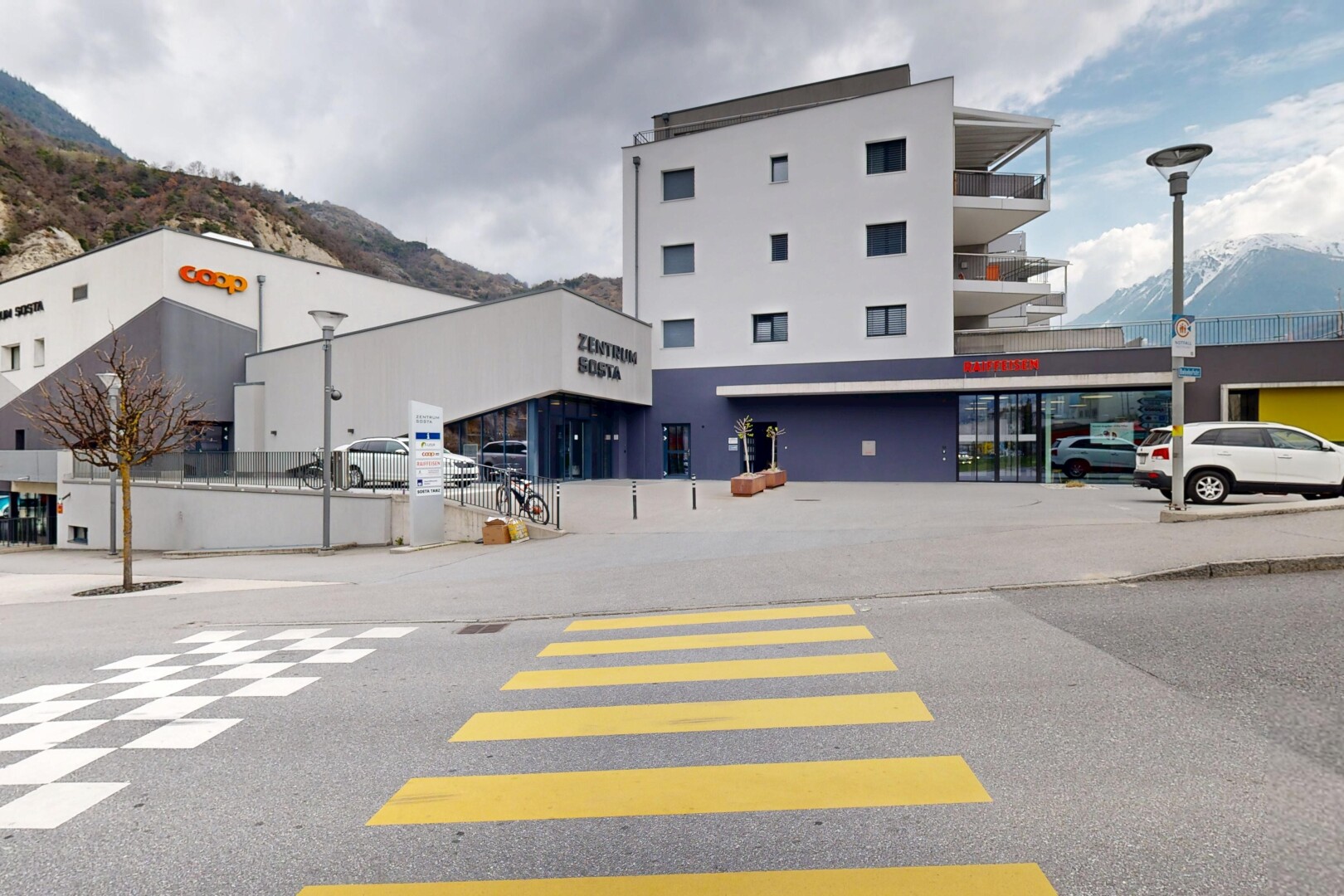 extérieur du bâtiment avec vue sur la montagne, parking, et vue commerciale