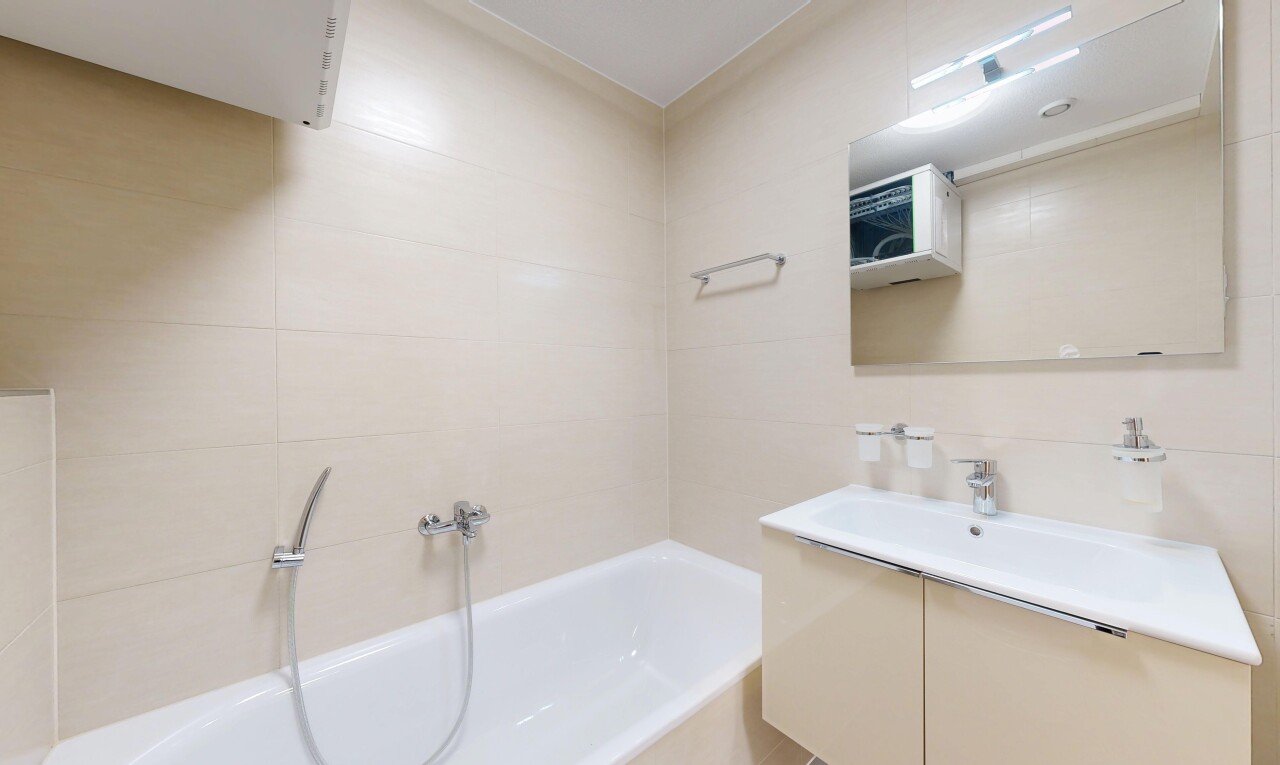 salle de bains avec salle de bain complète, lavabo (ou coiffeuse selon le contexte), mur en carrelage, bain, et miroir
