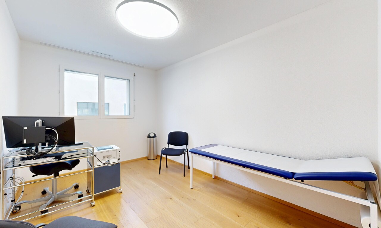 chambre avec télévision, cloison sèche, sol en finition bois, espace bureau, et lumière naturelle