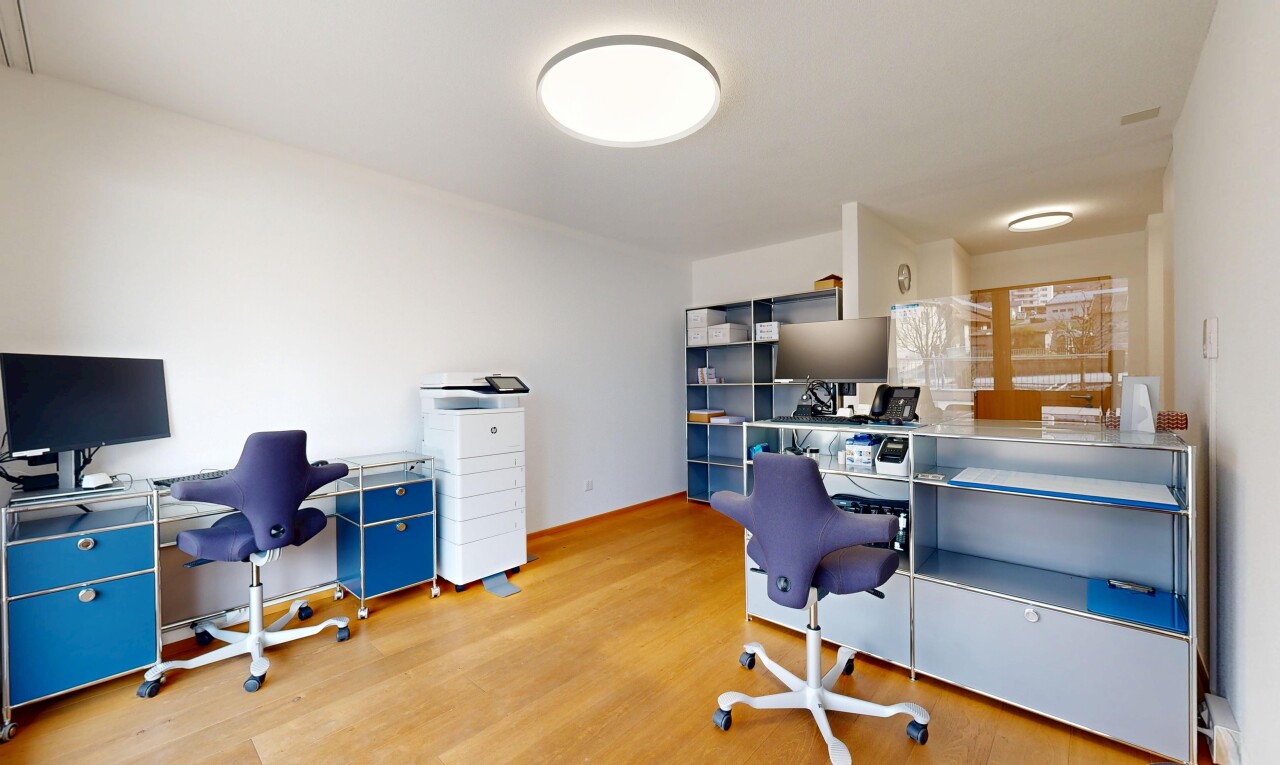 bureau avec espace bureau, télévision, et sol en finition bois