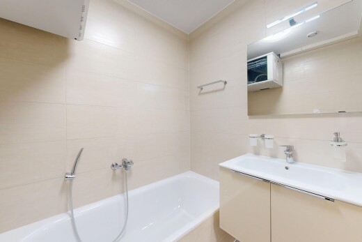 salle de bains avec salle de bain complète, lavabo (ou coiffeuse selon le contexte), mur en carrelage, bain, et miroir