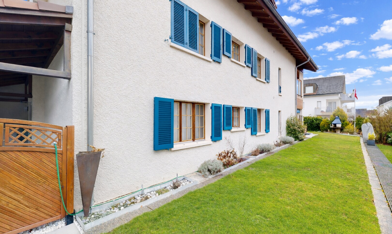 façade avec bardage en stuc, pelouse, property visible, et day time