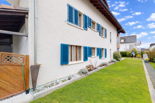 façade avec bardage en stuc, pelouse, property visible, et day time