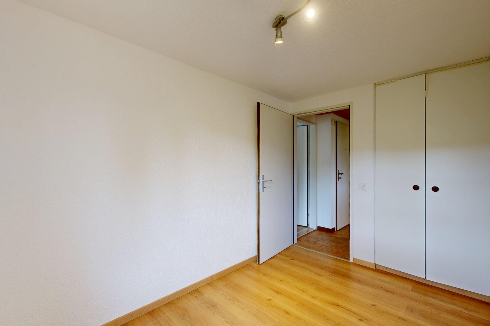 pièce vide avec inside property, cloison sèche, drywall, sol en finition bois, et wood finish floor