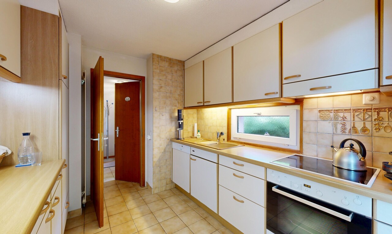 kitchen with oven, light countertops, black electric stovetop, backsplash, and light tile patterned flooring