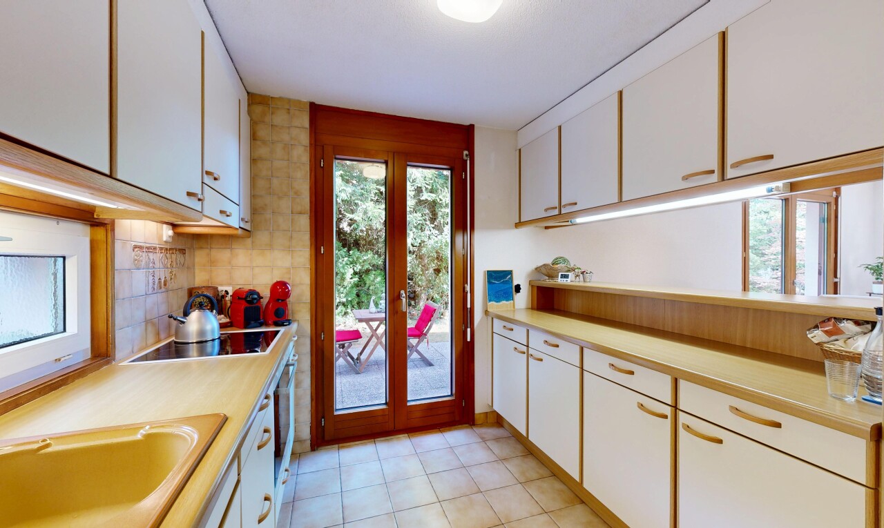 dual tone kitchen with light countertops, dual tone cabinets, decorative backsplash, black electric stovetop, and light tile patterned floors
