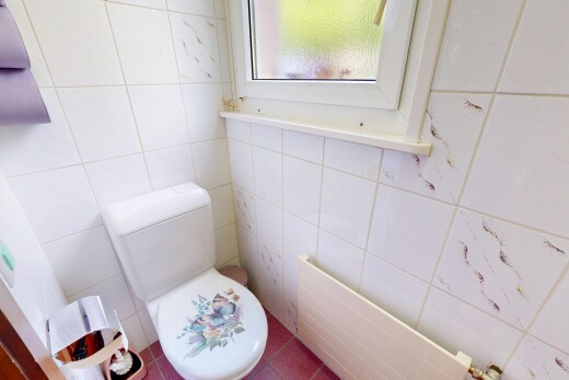 salle de bains avec toilette, tile wall, mur en carrelage, radiateur, et tile floor