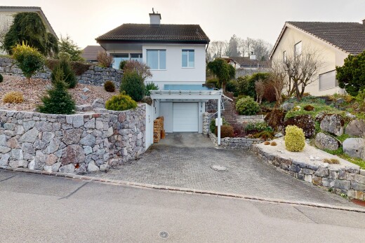 außenansicht mit eingebaute garage, property visible, stuckverkleidung, auffahrt, und schornstein