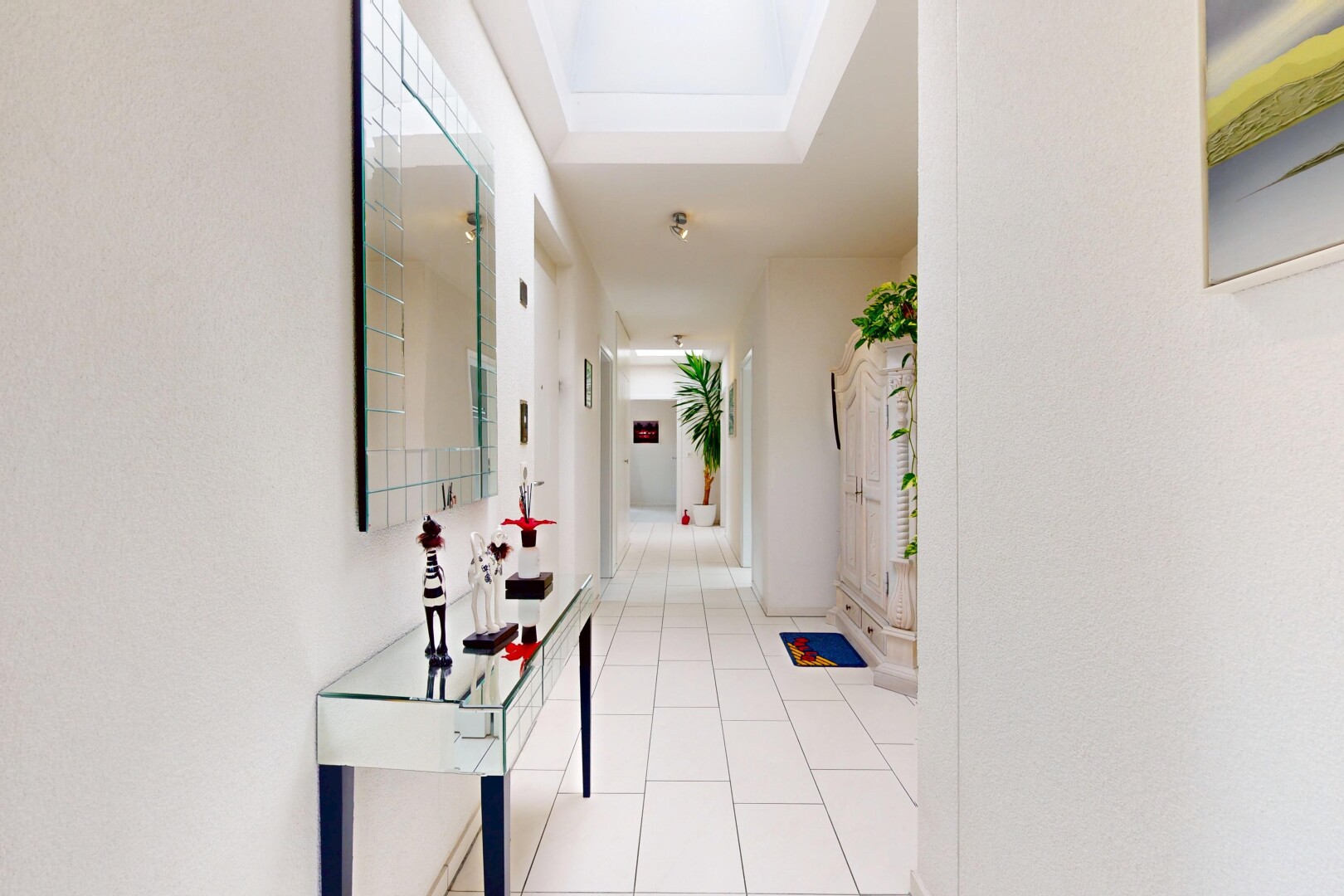 couloir avec inside community, tile floor, sol en carrelage, tray ceiling, et plafond à plateaux