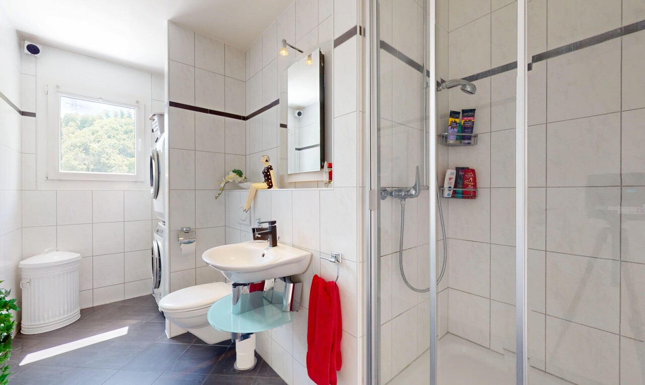 salle de bains avec lave-linge et sèche-linge superposés, tile wall, mur en carrelage, miroir, et douche