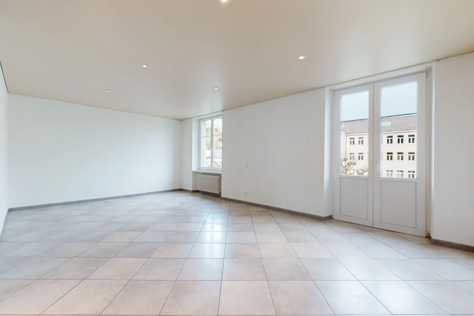 chambre vide avec lumière naturelle, carrelage, et radiateur