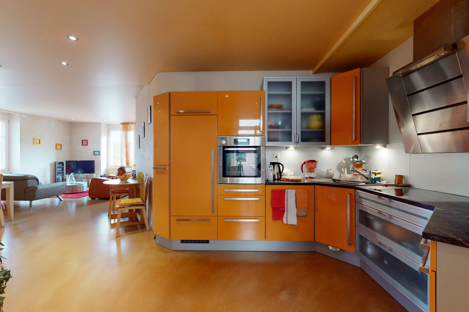cuisine avec acier inoxydable, hotte, four, sol clair, plan de travail foncé, et meubles marron