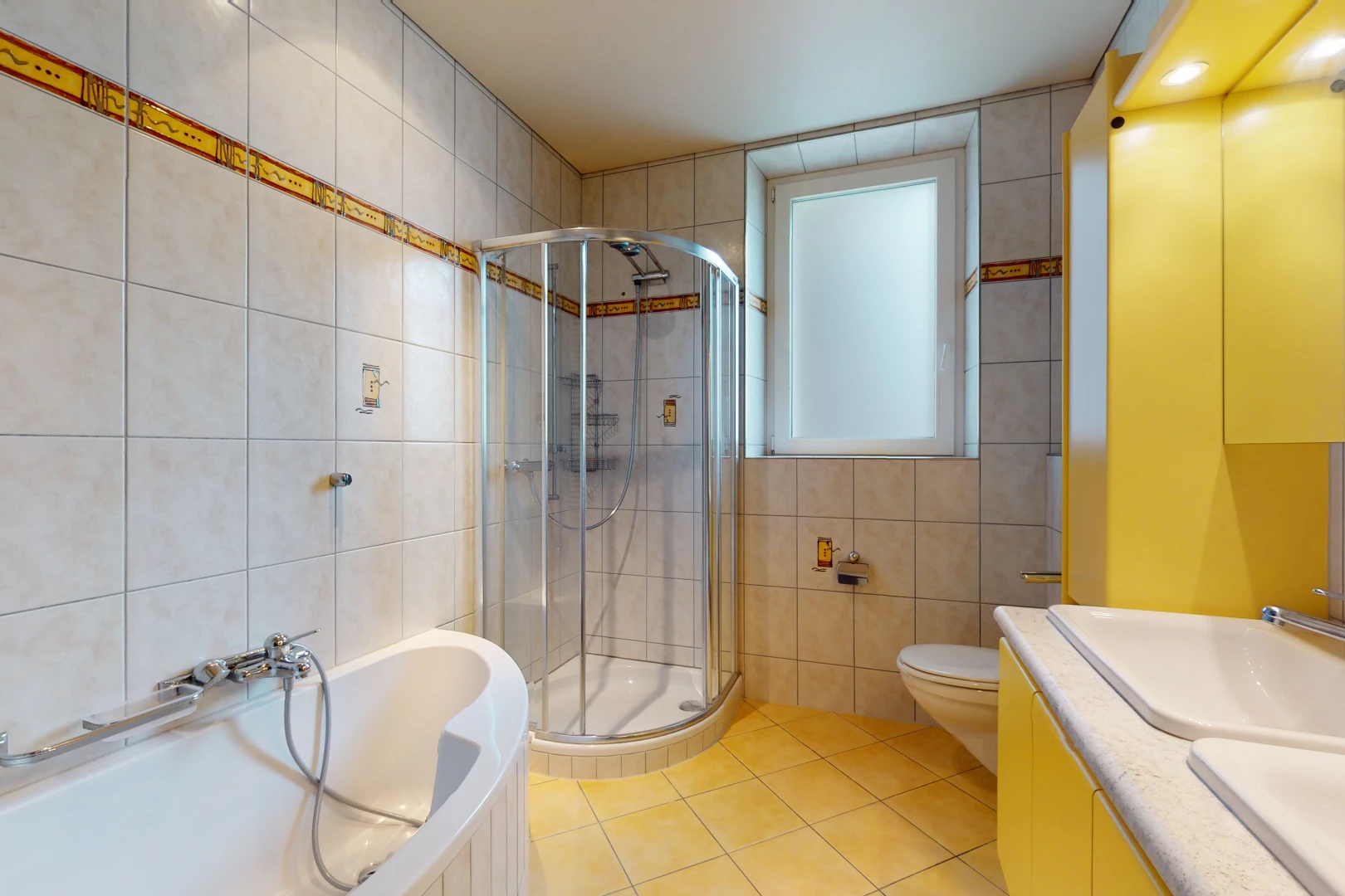 salle de bains avec carrelage, porte de douche, vasque, meuble-lavabo, douche, toilettes, baignoire, et miroir