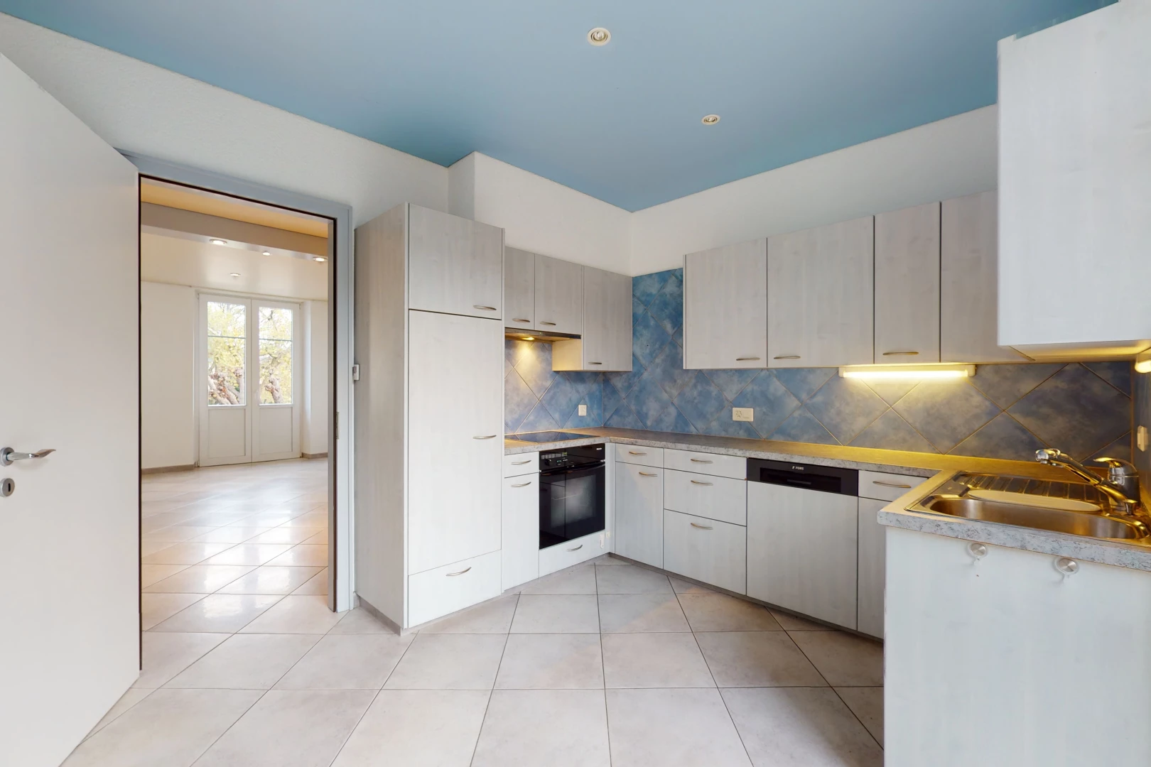 cuisine avec lumière naturelle, carrelage, four, lave-vaisselle, sol clair, et meubles blancs