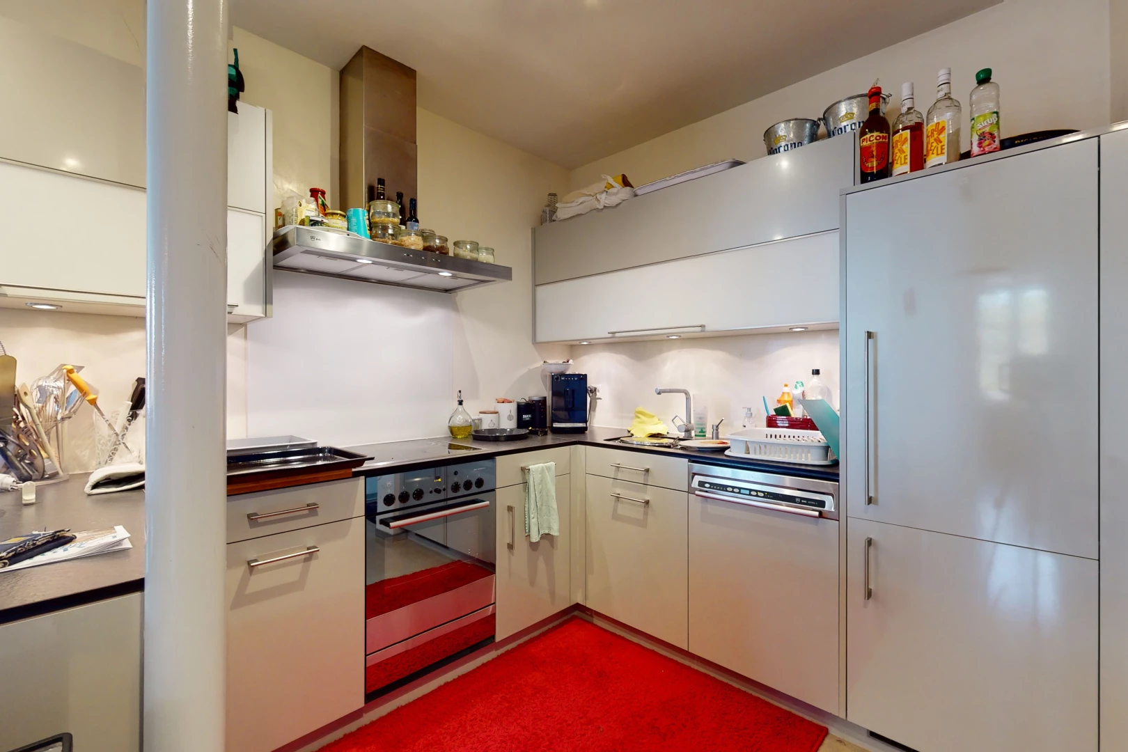 cuisine avec acier inoxydable, four, hotte, plan de travail foncé, et meubles blancs