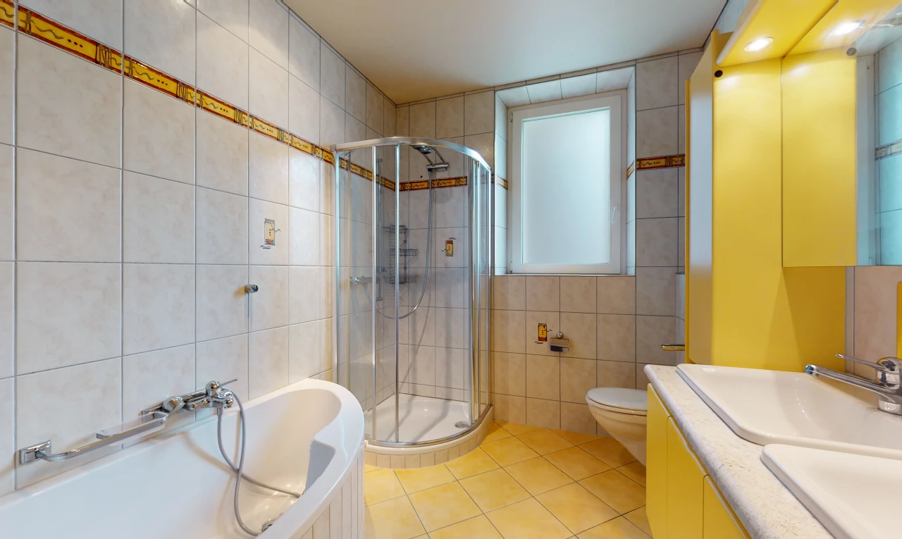 salle de bains avec carrelage, porte de douche, vasque, meuble-lavabo, douche, toilettes, baignoire, et miroir