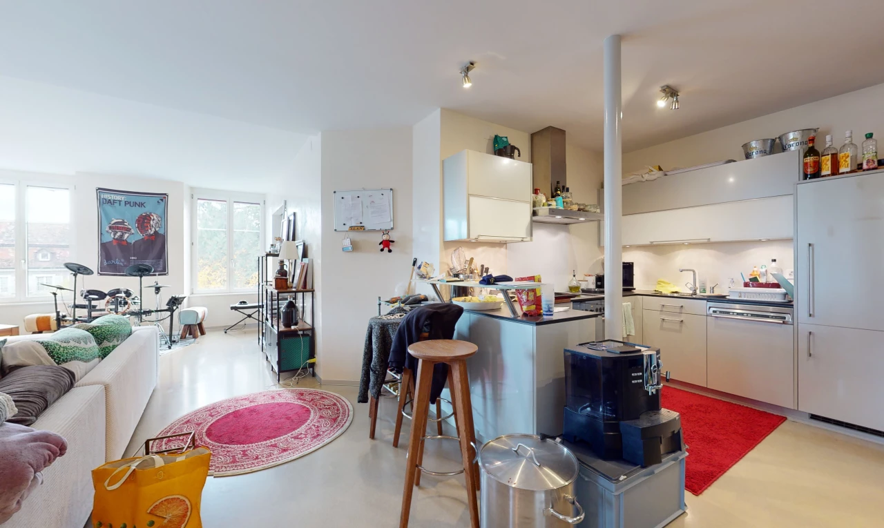 cuisine avec lumière naturelle, bar, hotte, plan de travail foncé, et sol clair