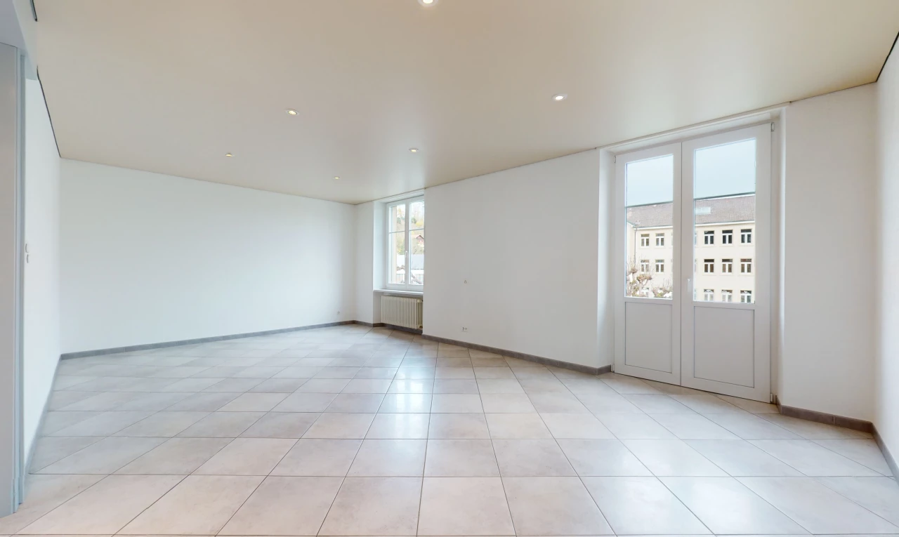 chambre vide avec lumière naturelle, carrelage, et radiateur