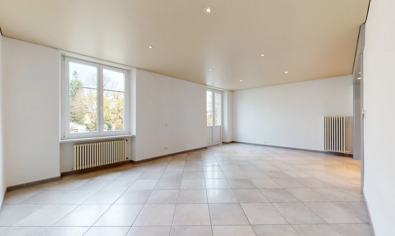 chambre vide avec lumière naturelle, carrelage, et radiateur