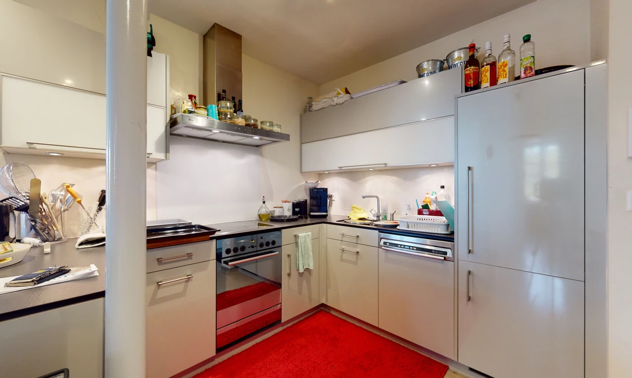 cuisine avec acier inoxydable, four, hotte, plan de travail foncé, et meubles blancs