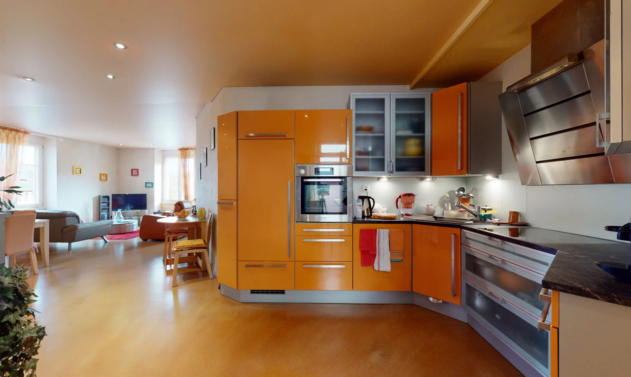 cuisine avec acier inoxydable, hotte, four, sol clair, plan de travail foncé, et meubles marron