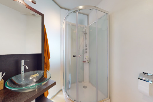 badezimmer mit dusche mit duschtür, waschtisch mit umfangreichem schrankraum und spiegel