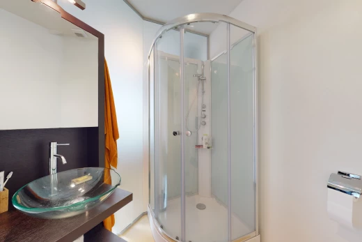 salle de bains avec vasque, porte de douche, miroir, meuble-lavabo, et douche