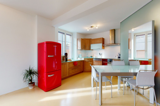 küche mit einer gesunden menge an sonnenlicht, abgashaube, braunen schränken, hellen böden und hellen arbeitsplatten